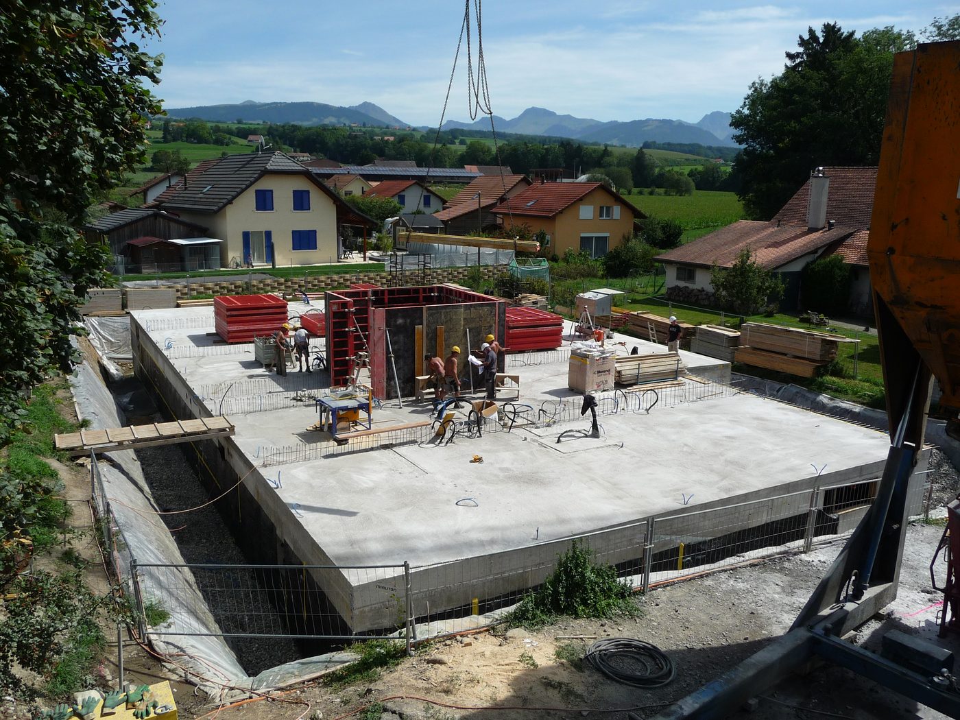 Chantier en cours : la dalle est coulée, les ouvriers montent les coffrages des premiers murs