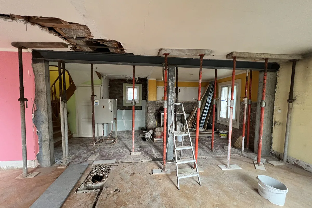 L'intérieur de la maison vidé, poutre métallique posée et étais rouges sous le plancher