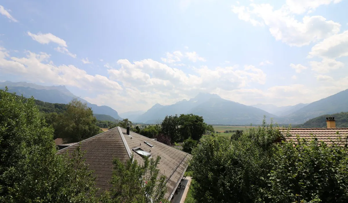 Vue depuis Ollon sur les toits du village, la plaine du Rhône et les montagnes du Chablais