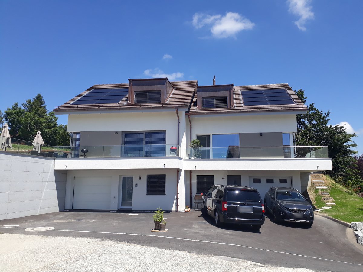 Les deux villas jumelles de Servion terminées, leurs garages au rez et les panneaux solaires sur le toit
